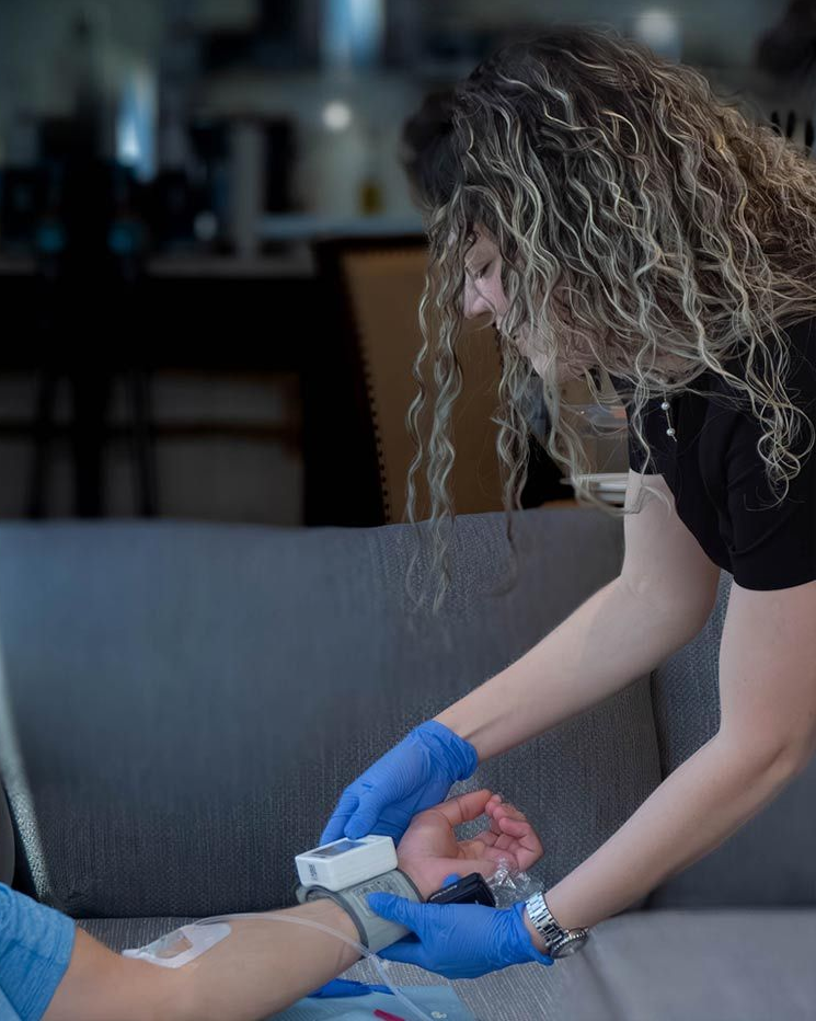 Person getting medical check. A person wearing blue gloves checks the other person's wrist with a medical device indoors.