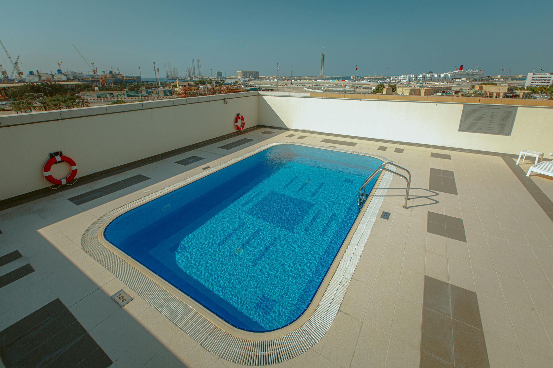 Rooftop swimming pool with bright blue water and white deck overlooking a city skyline