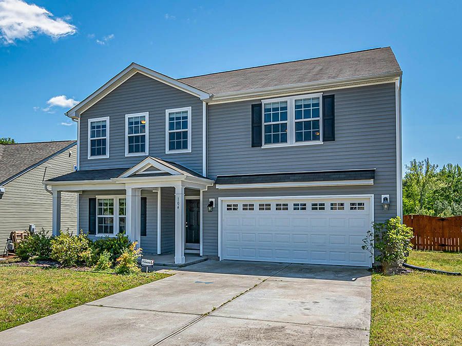 A large gray house with a white garage door and a porch.