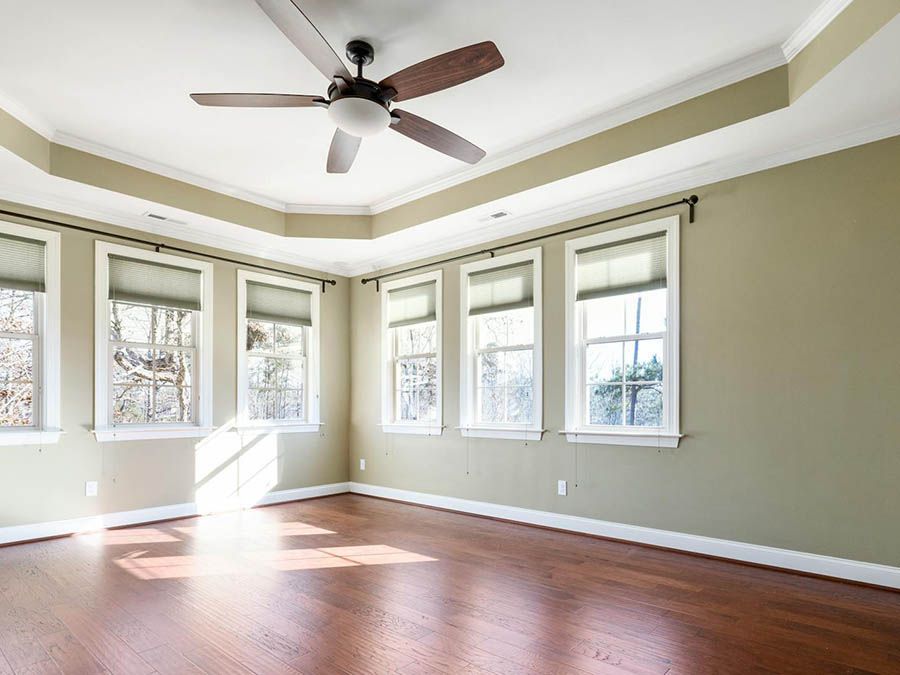 An empty room with hardwood floors and a ceiling fan.