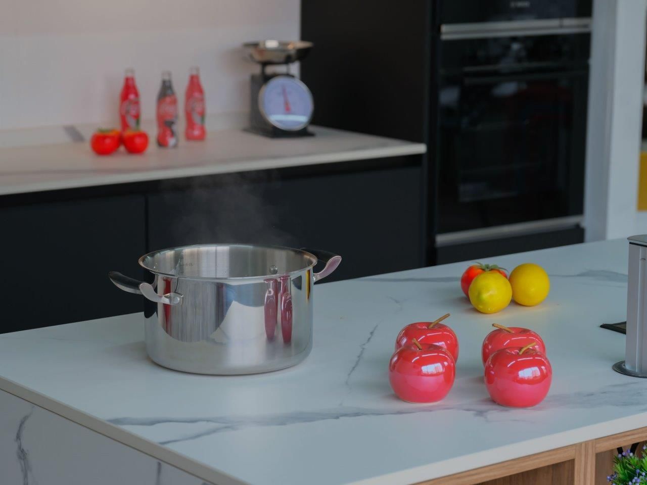 Una pentola è appoggiata sul tavolo della cucina accanto a mele e limoni.