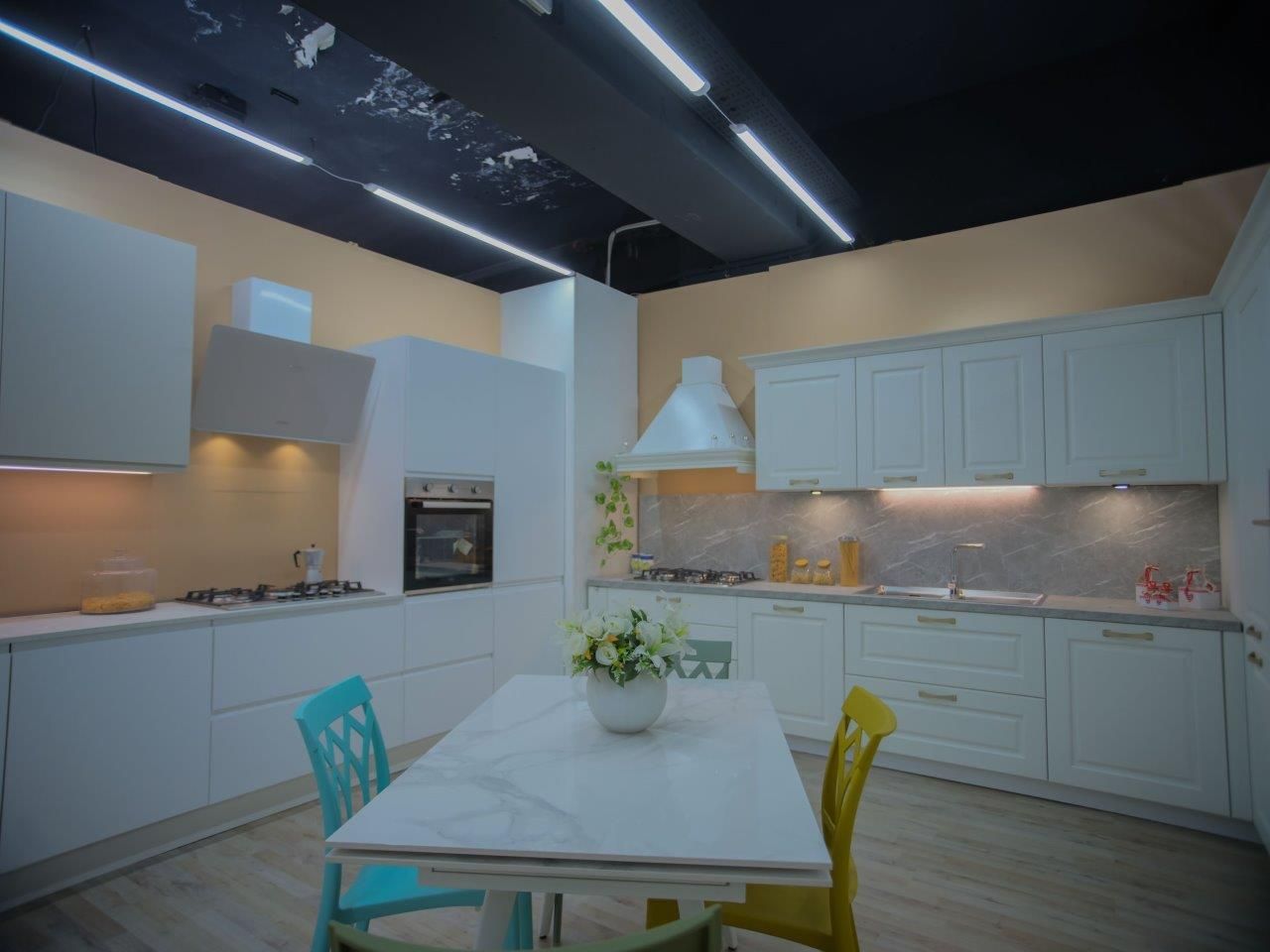 Una cucina con mobili bianchi, un tavolo e sedie.