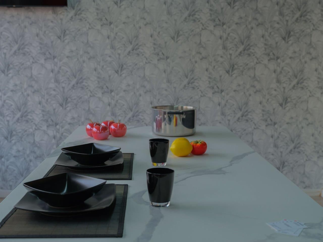 Un tavolo con piatti, ciotole, bicchieri e frutta.