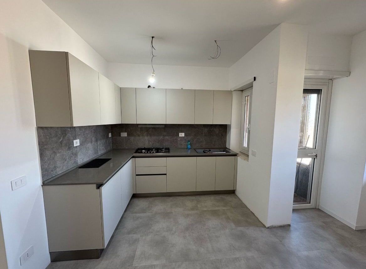 Una cucina con mobili bianchi e un piano di lavoro grigio