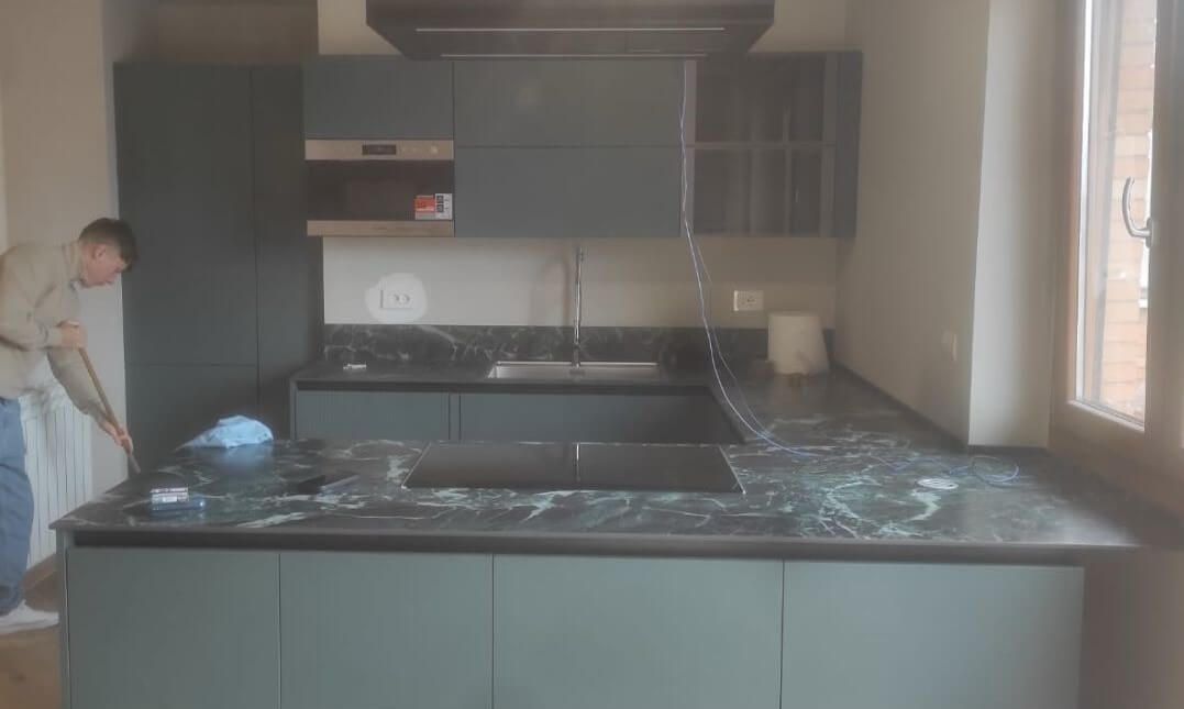 Un uomo è in piedi in cucina accanto a una finestra.