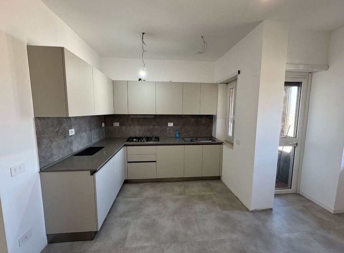 Una cucina con mobili bianchi e un piano di lavoro grigio.