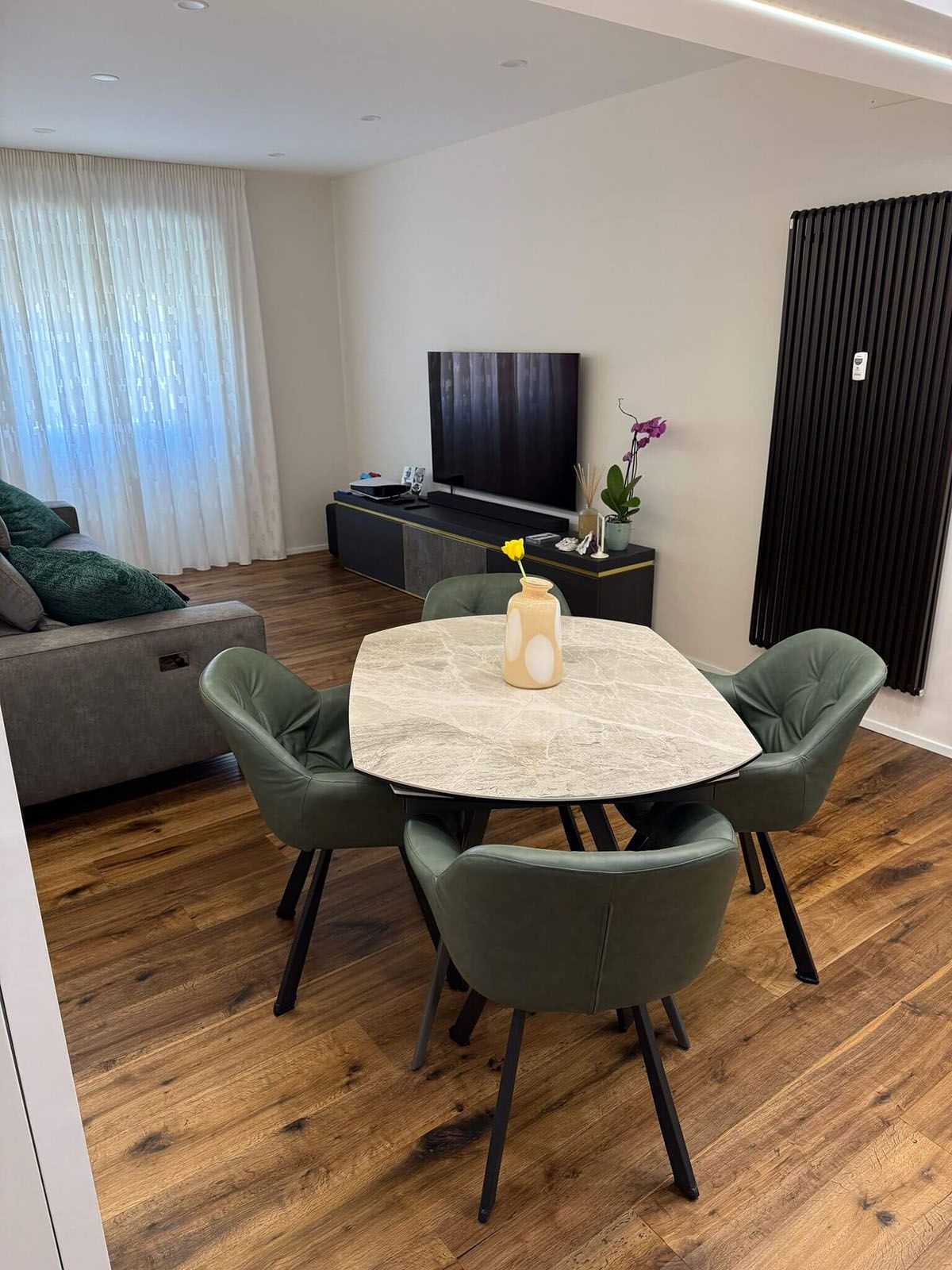 Un soggiorno con tavolo, sedie e TV a schermo piatto.