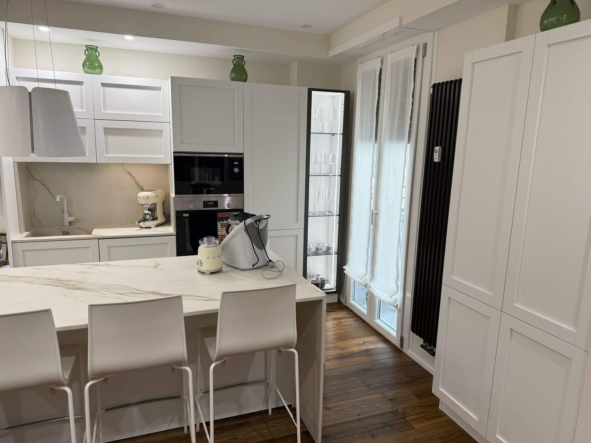 Una cucina con mobili e sgabelli bianchi e una grande isola.