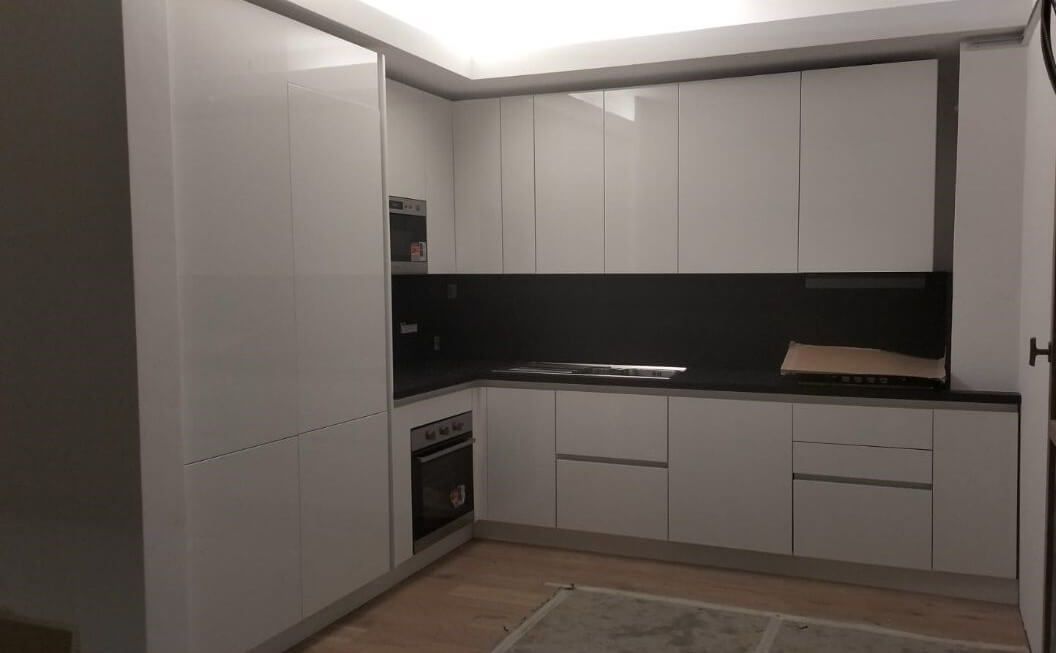 Una cucina con mobili bianchi e ripiani neri