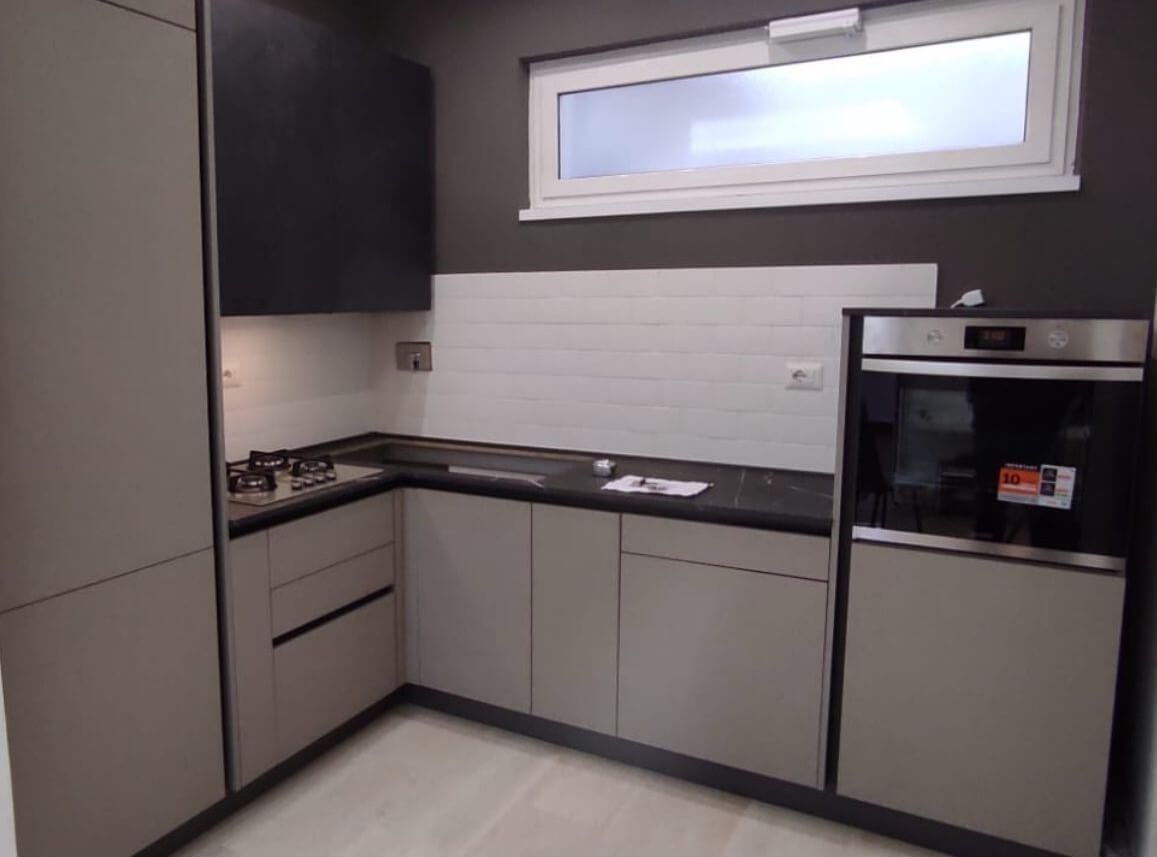 Una cucina con mobili bianchi e ripiani neri