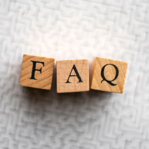 Wooden letter blocks spelling “FAQ” on a light textured background.