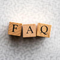 Wooden letter blocks spelling “FAQ” on a light textured background.