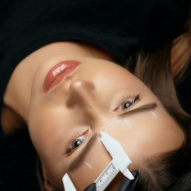 Close-up of a face with a white clothespin on the nose, lying upside down against a dark background