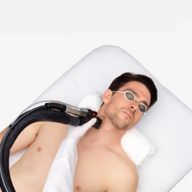 Man lying on a white treatment bed with a device placed on his neck and shoulder