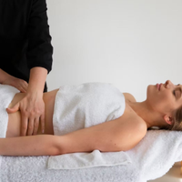 Massage therapist pressing a client’s lower back during a spa treatment on a table