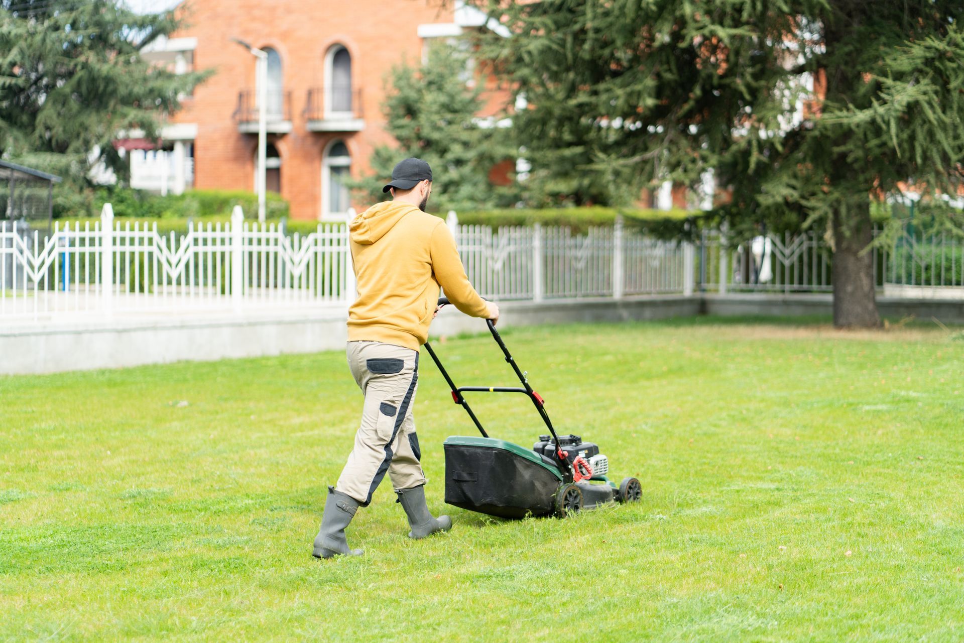A man is using a lawn mower to cut the grass in a park.