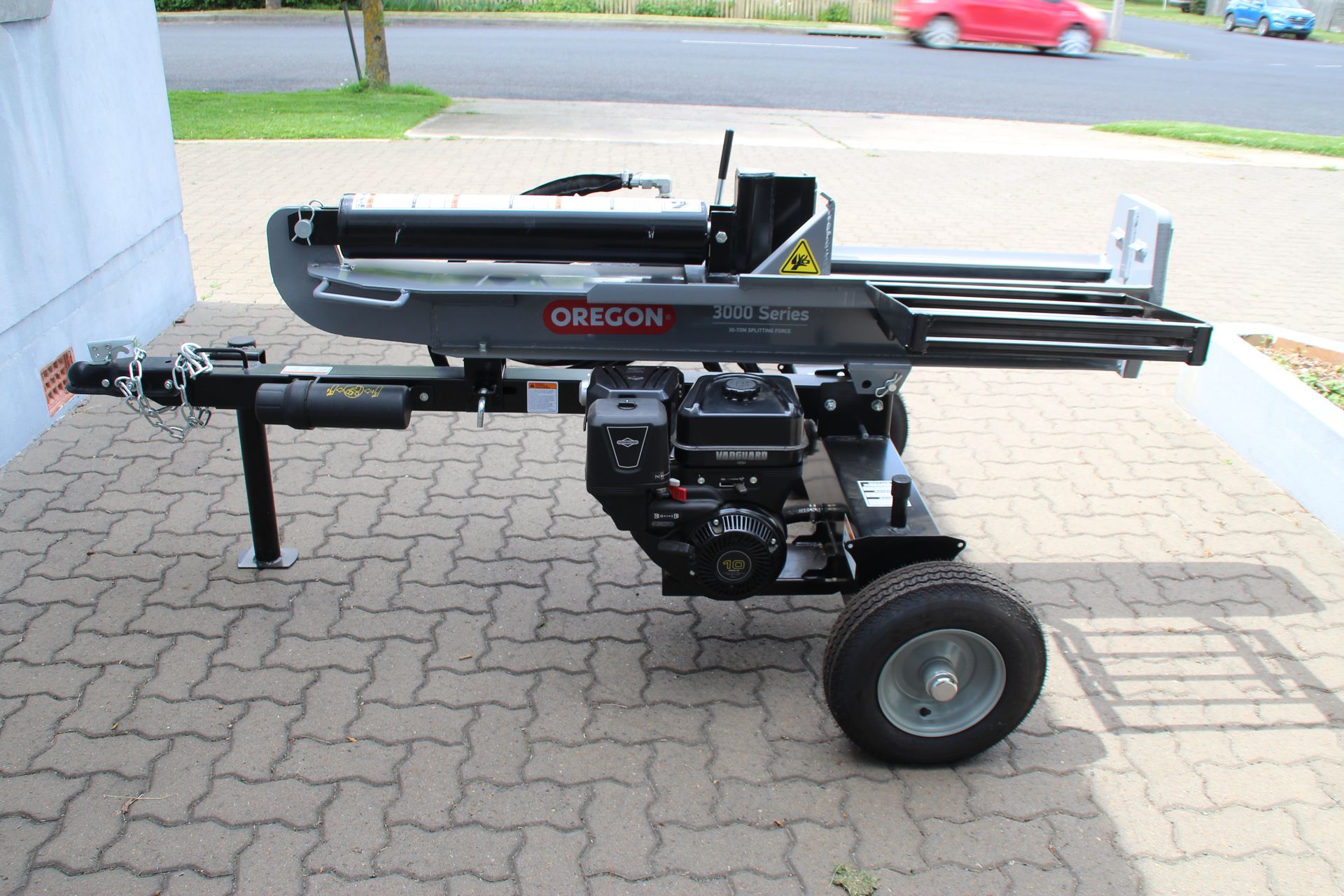 A grey wood splitter on a black trailer with motor.