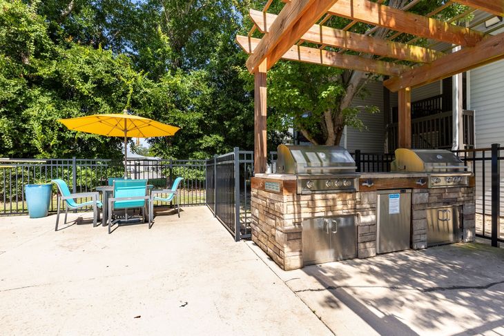 Outdoor grilling area with two grills, seating, and a yellow umbrella.