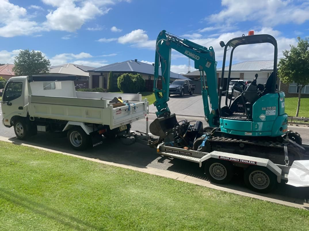 A Small Excavator Is Being Towed — R&J Cronin Equipment Hire in Bonnells Bay, NSW