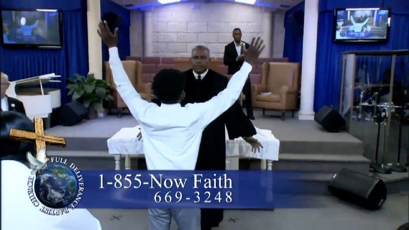 Man with arms raised in church with pastor, blue decor, 1-855-Now Faith phone number.