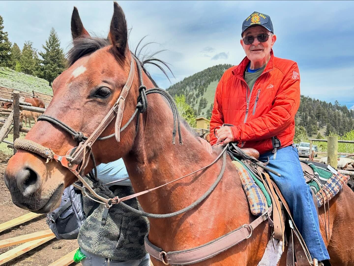 A man in an orange jacket is riding a brown horse.