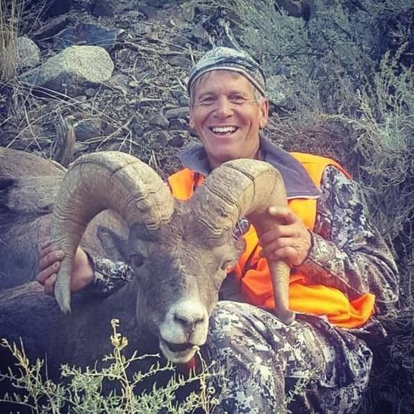 A man posing with a dead ram