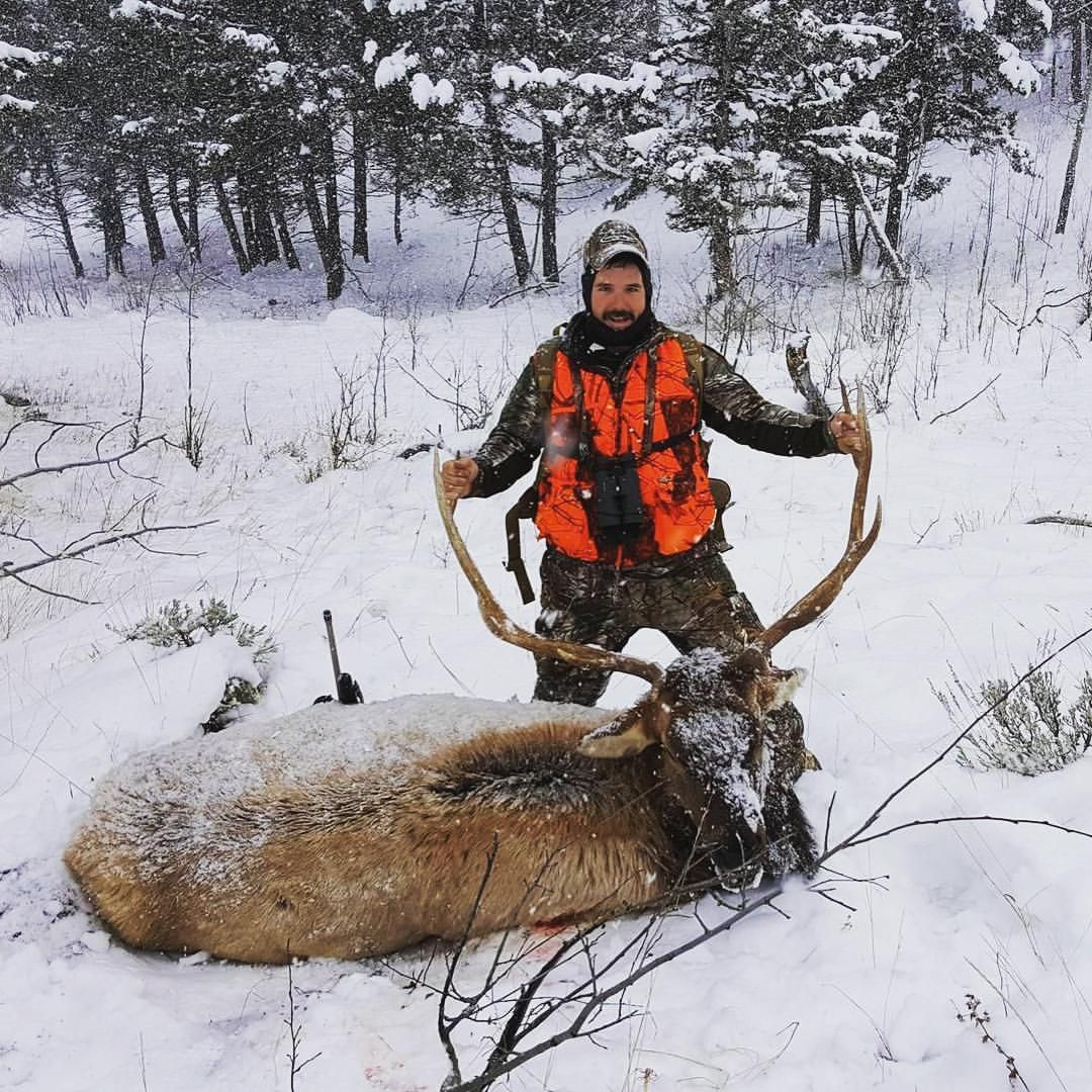 A man posing with a dead deer