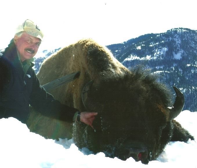 A man laying next to a bison in the snow