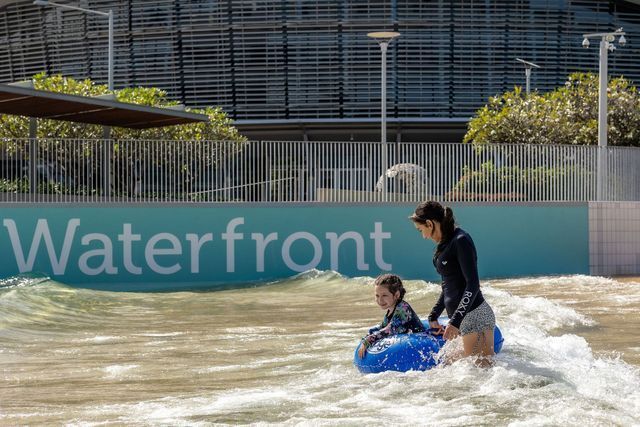 A woman and child in a blue inflatable float in a wave pool, with a 