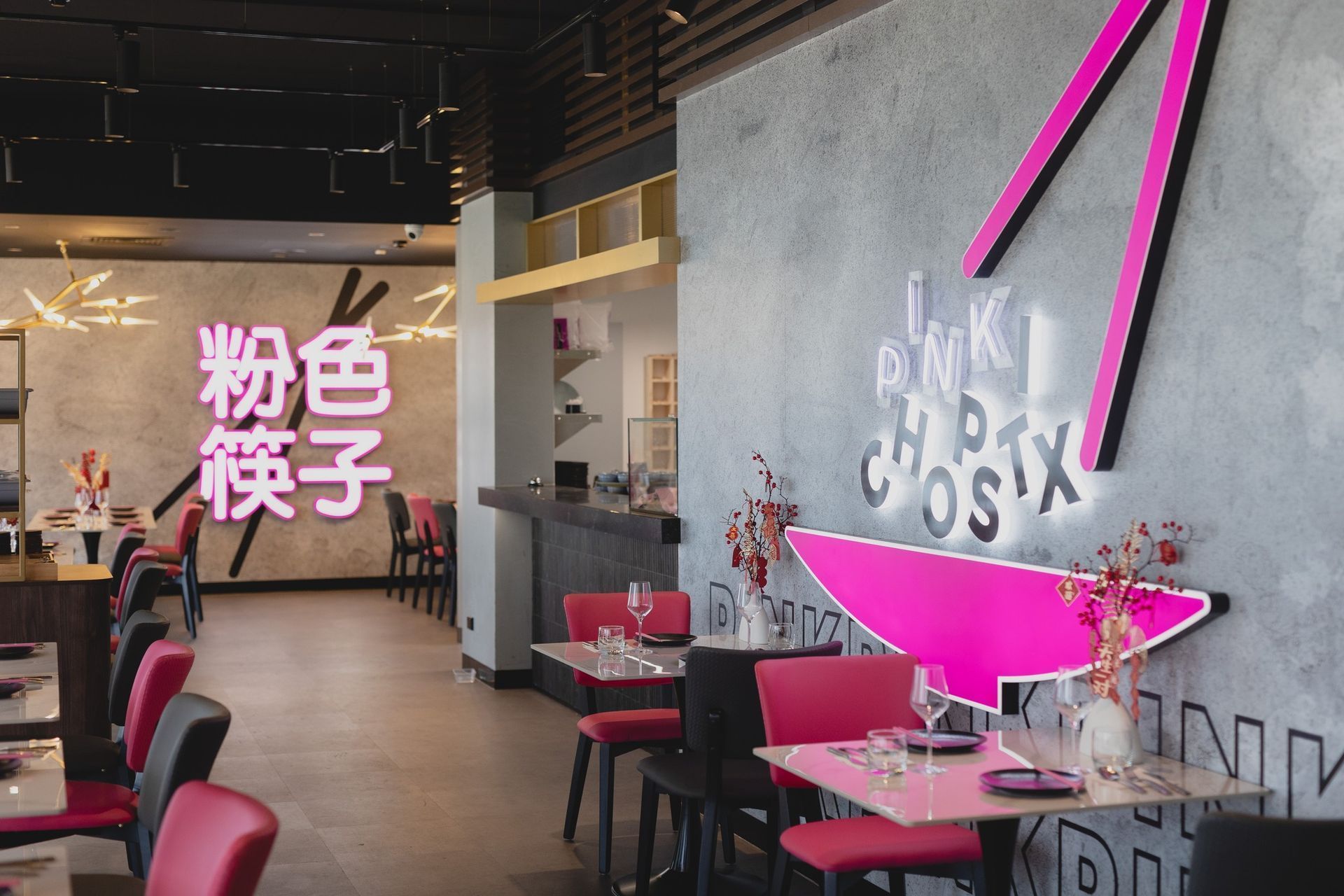 Pink Chopstx restaurant interior with pink neon signs and tables.