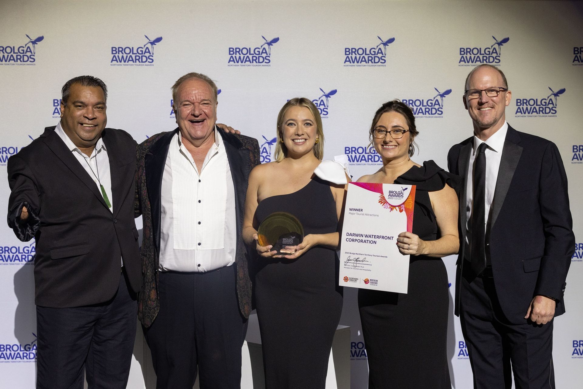 Five people at an awards ceremony, holding a trophy and certificate.