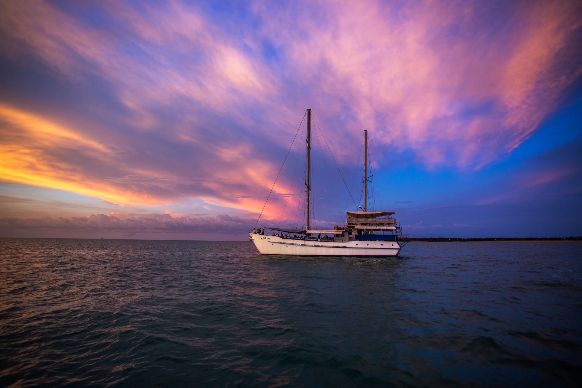 Sailboat on calm water with vibrant sunset sky.