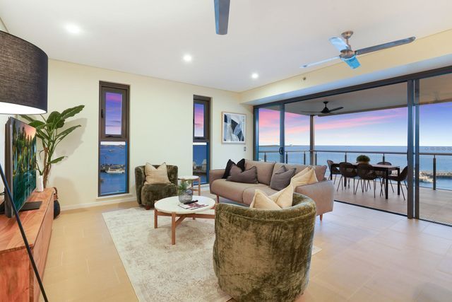 Modern living room with ocean view, sofa, armchairs, and balcony access.