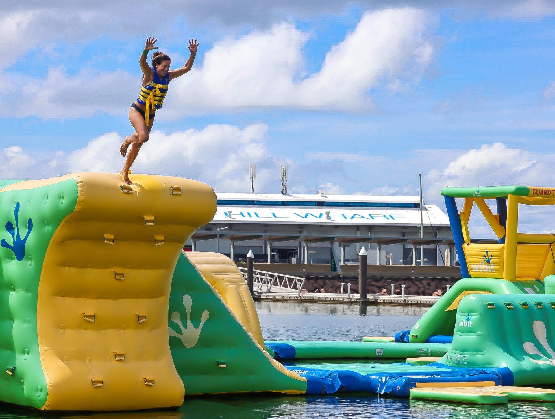 Woman jumping off inflatable water obstacle course.