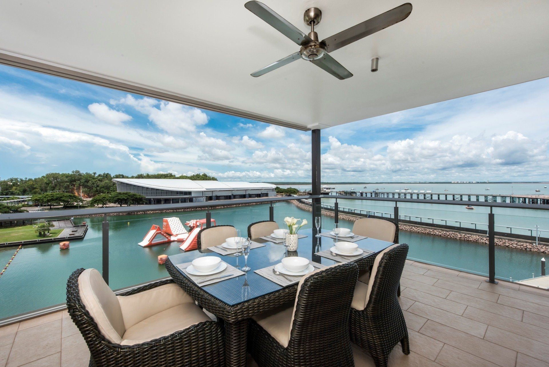Outdoor dining area overlooking a harbor with water activities and a blue sky.