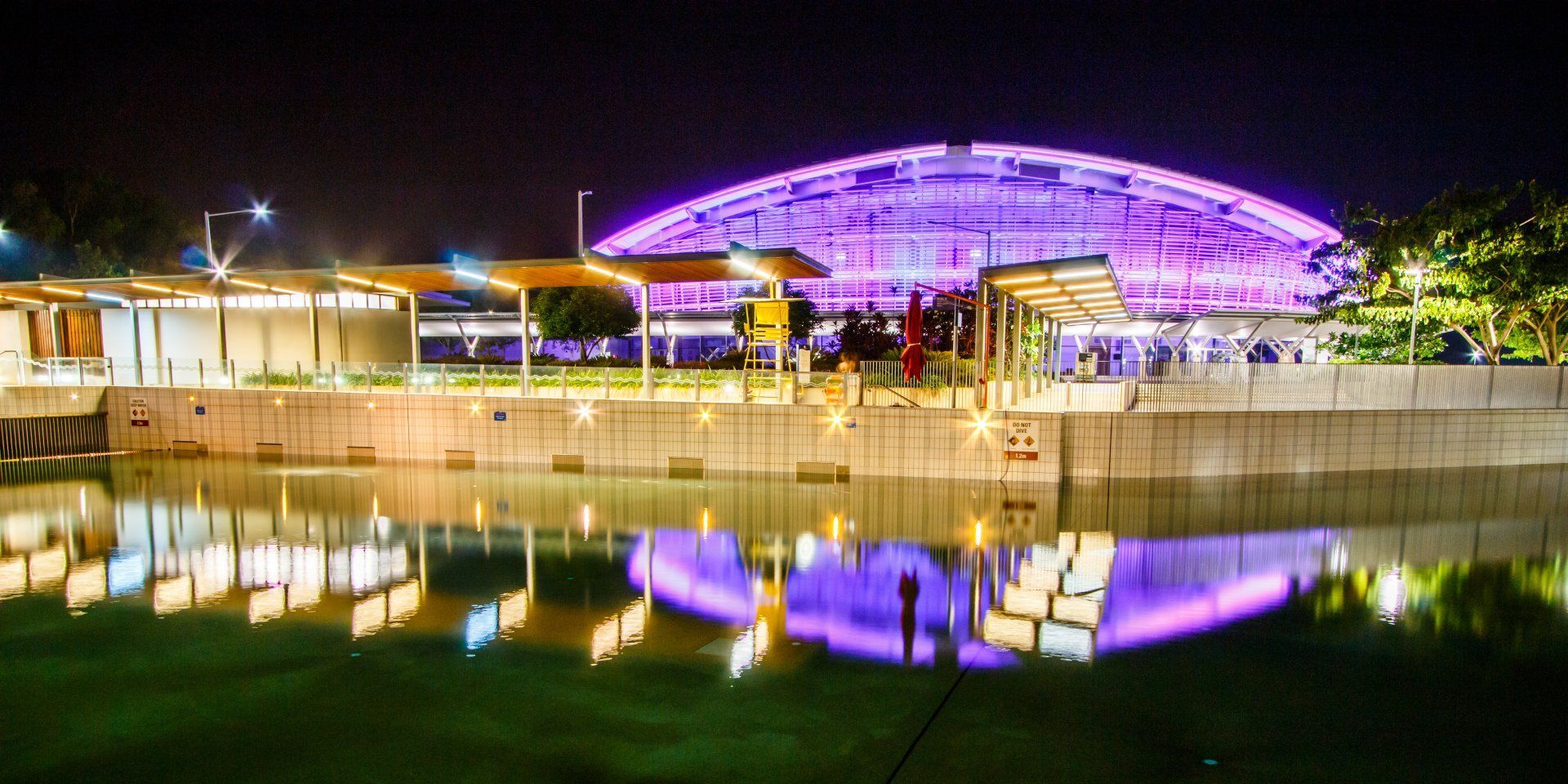 Lights reflecting on the water of the Wave Lagoon with the Darwin Convention Centre lit up in the background