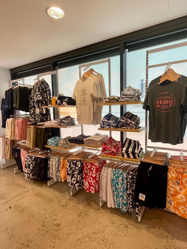 Clothing store display with shelves and hanging shirts and shorts.