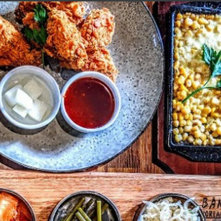 Korean fried chicken, corn cheese, and side dishes on a wooden table.