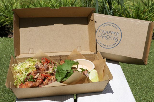 Takeout meal in a cardboard box, including salad, meat, sauce, lime, with 