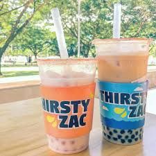 Two boba teas with straws in branded cups on a table outdoors.