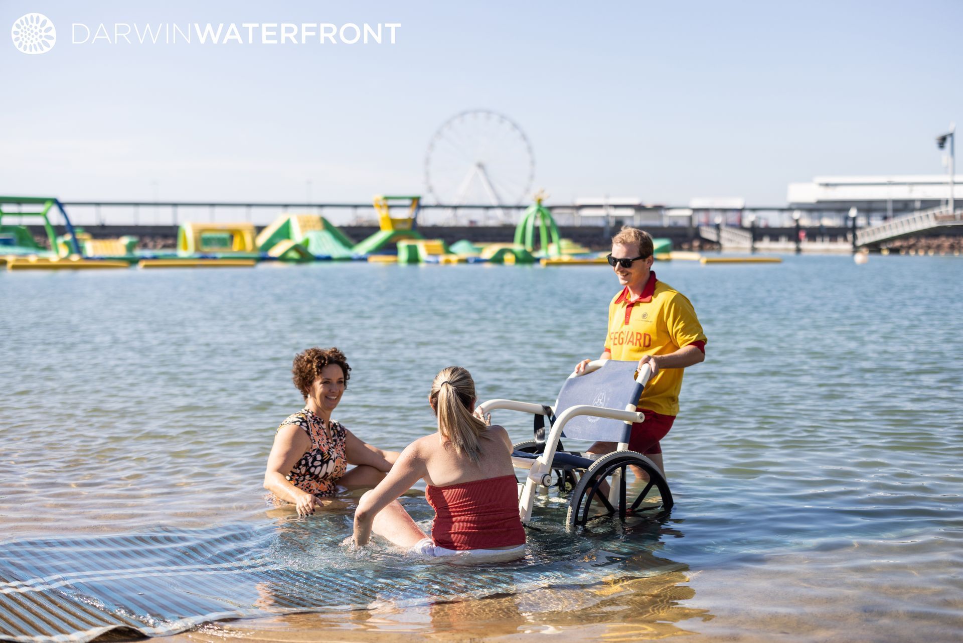 People in water, one in wheelchair, with lifeguard at Darwin Waterfront.