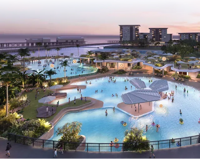 Large lagoon with people swimming and relaxing, surrounded by buildings and palm trees.