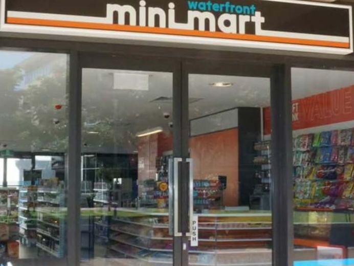 "Entrance to a miniMart convenience store with glass doors, storefront sign: 'miniMart waterfront'."