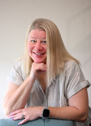 A woman is smiling with her hand on her chin and wearing a watch.