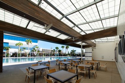 A large room with tables and chairs and a pool in the background