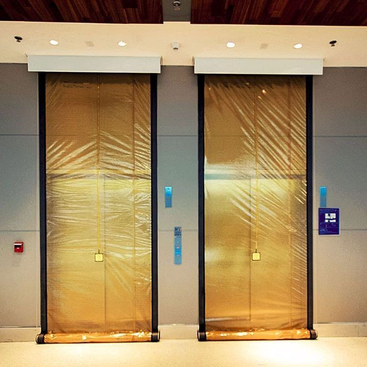 Two elevators in a building with a fire alarm on the wall