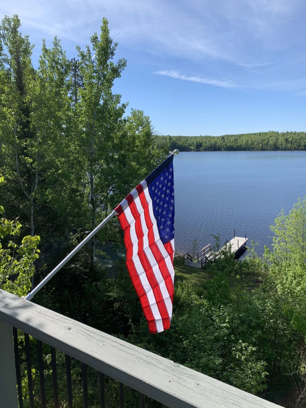 An american flag is flying on a balcony overlooking a lake.