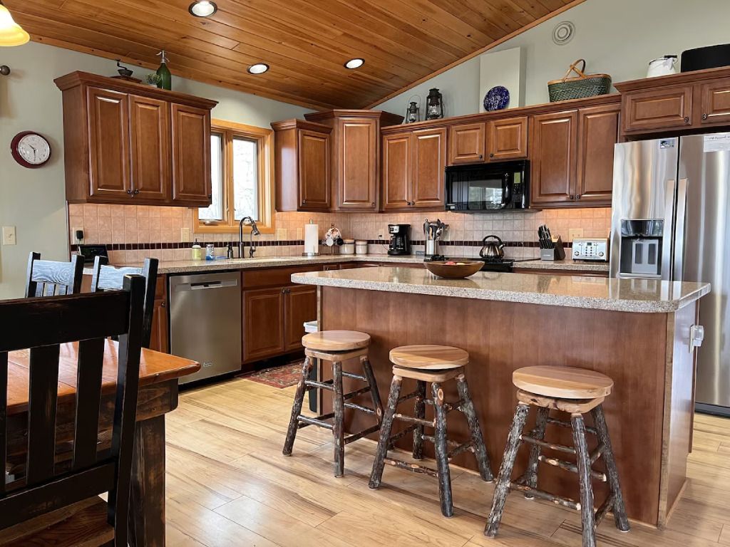A kitchen with wooden cabinets , stainless steel appliances , and a large island.