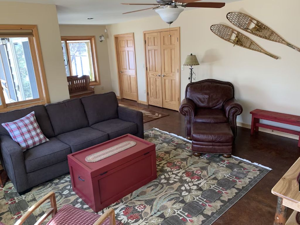 A living room with a couch , chair , coffee table and a ceiling fan.