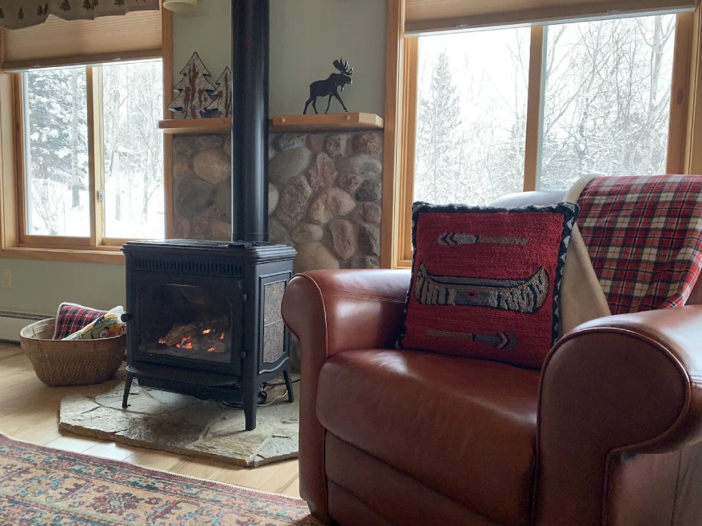 A living room with a leather chair and a wood stove.